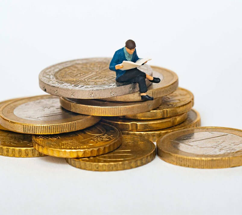 A successful investor reading a newspaper and sitting comfortably sitting on all the coins and profits gotten from investing in the Nigerian stock market